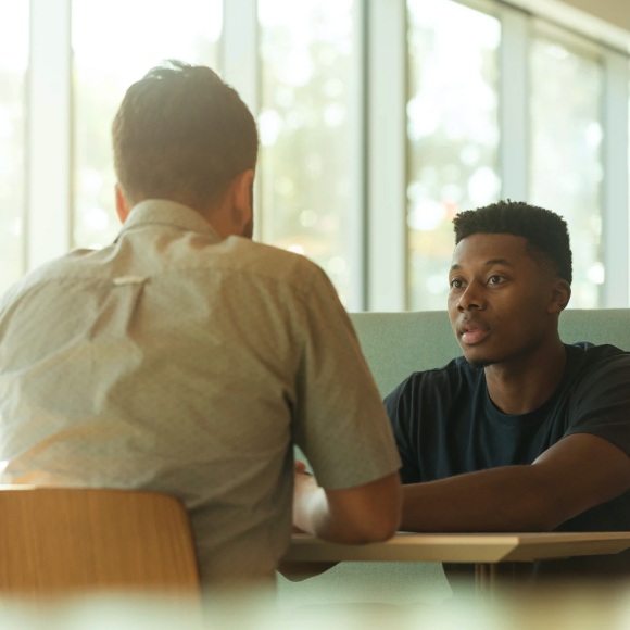 Young man sitting at a diner, talking with someone.