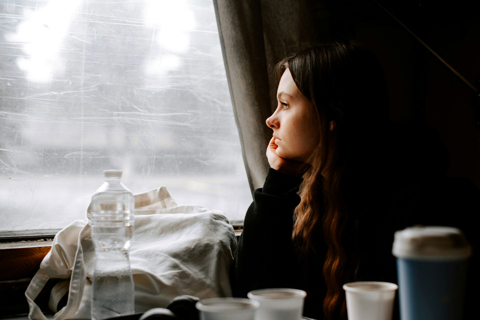 Picture of a young woman looking pensively out the window.